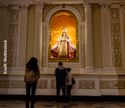 A young woman presents her respects in front of the image of the Virgin of Chapi in the central chapel of the Cathedral of Arequipa