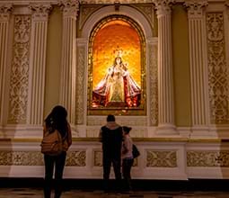 A young woman pays her respects in front of the image of the Virgin of Chapi in the central chapel of the Cathedral of Arequipa