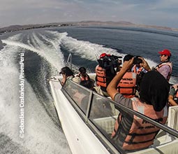 Turistas tirando fotos durante o passeio de iate em Paracas