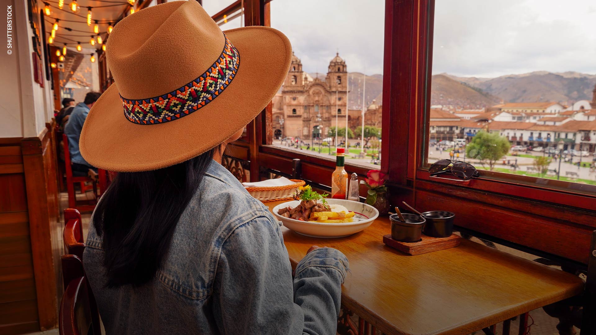 Turista almorzando y mirando la plaza del Cusco